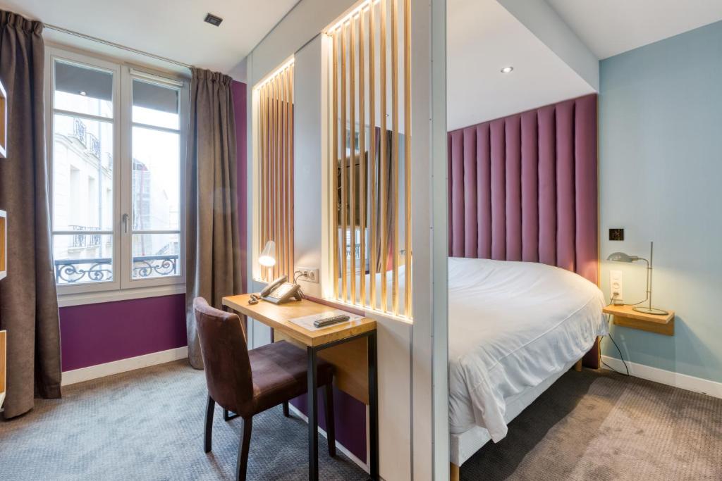 a hotel room with a bed and a desk with a chair at Hôtel du Jeu de Paume in Versailles
