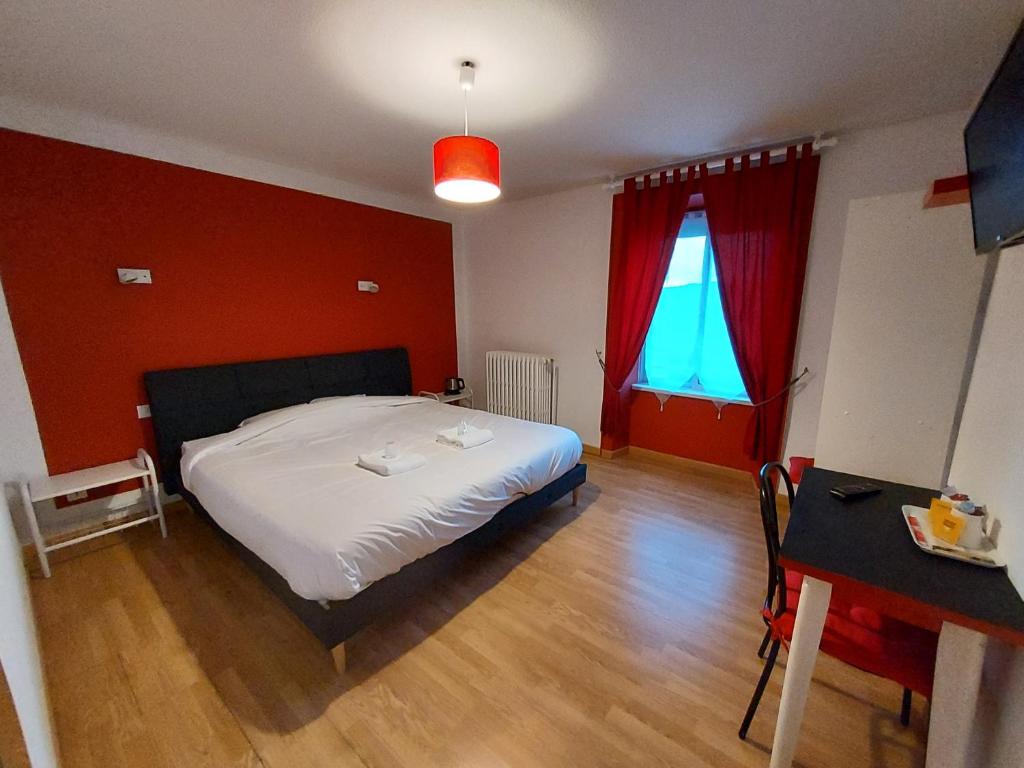 sypialnia z łóżkiem i czerwoną ścianą w obiekcie Hôtel le Comtois w mieście Saône