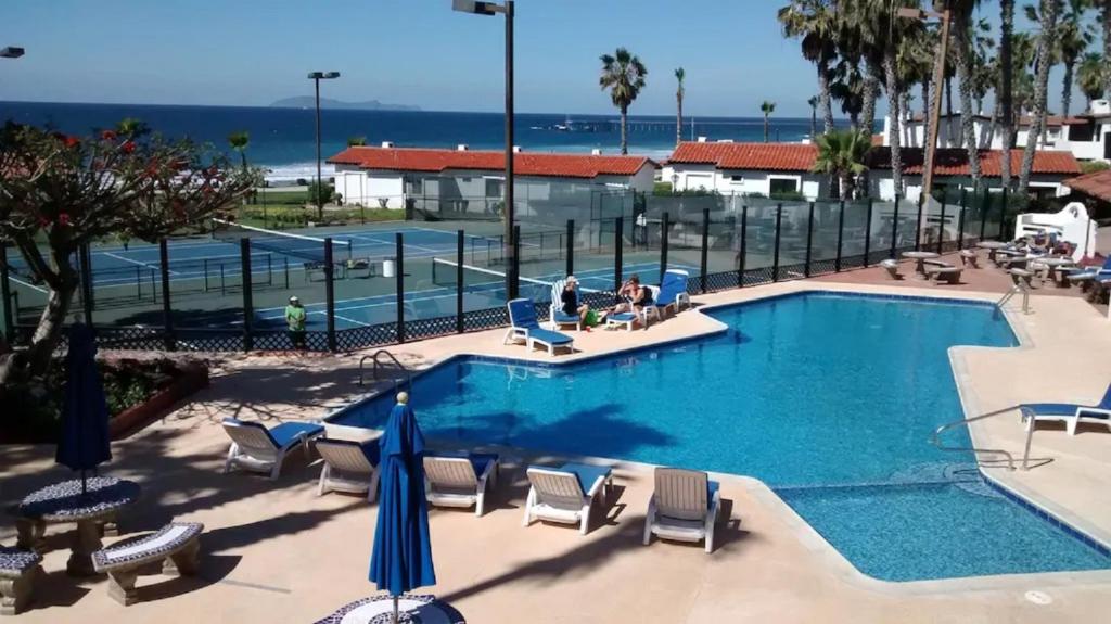 uma piscina com cadeiras e guarda-sóis em Great Beach Swiming Pools Tennis Courts Condo in La Paloma Rosarito Beach em Rosarito