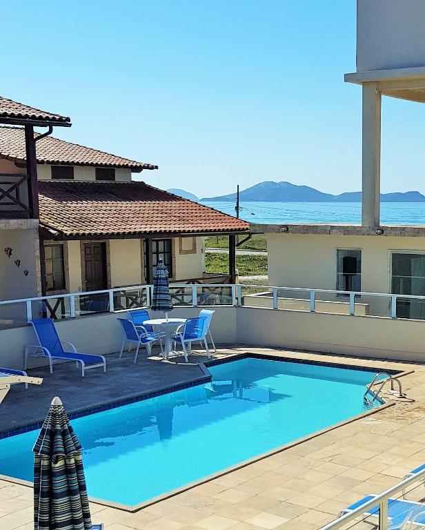 a swimming pool with a table and chairs on a house at Conforto e lazer com vista para o mar - Praia das Dunas Beach House in Cabo Frio