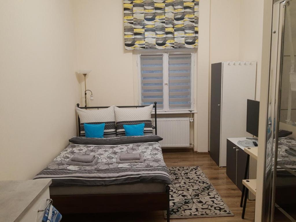 Un dormitorio con una cama con almohadas azules y una ventana en noclegi przy dworcu PKP en Breslavia