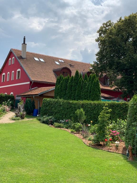 czerwony dom z ogródkiem z krzakami i drzewami w obiekcie Hotel Penzion Trámky w mieście Vikýřovice