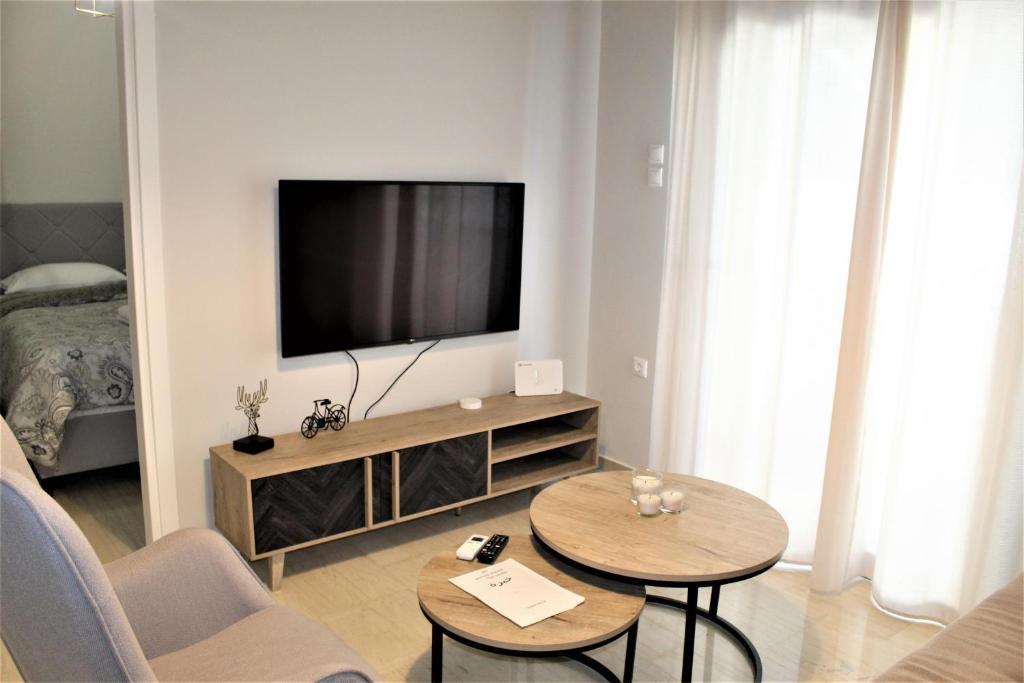 ein Wohnzimmer mit einem TV und 2 Tischen in der Unterkunft Khibra 2 in Volos