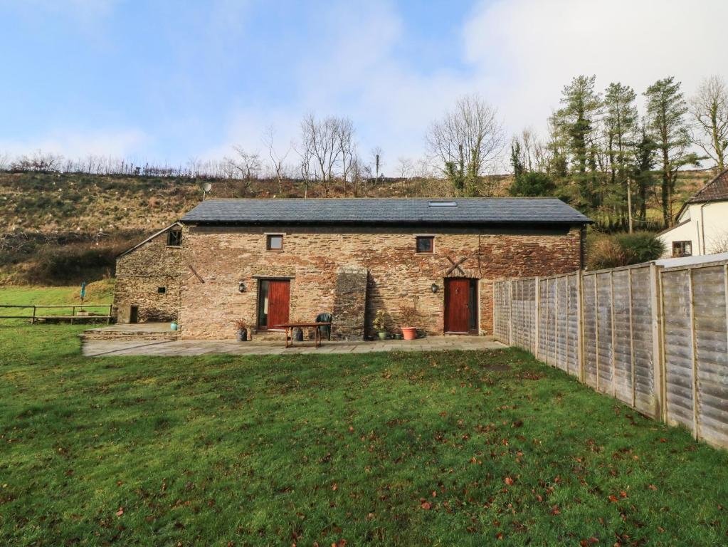 a stone house with a fence in a yard at Red Deer Cottage in Minehead