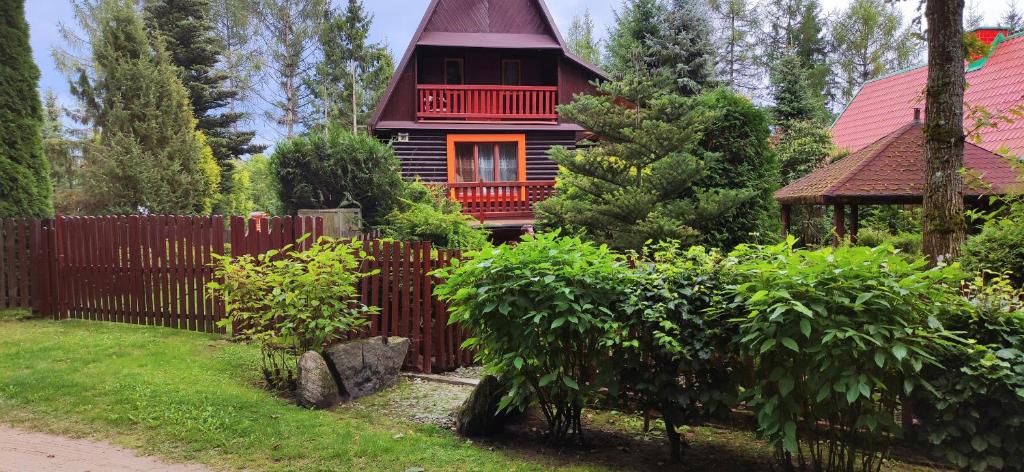 una casa roja con una valla delante de un patio en Domek nad jeziorem w otulinie lasu, en Bartołty Wielkie