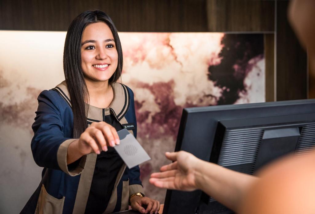 a woman is handing a piece of paper to a person at Pullman Miami Airport in Miami