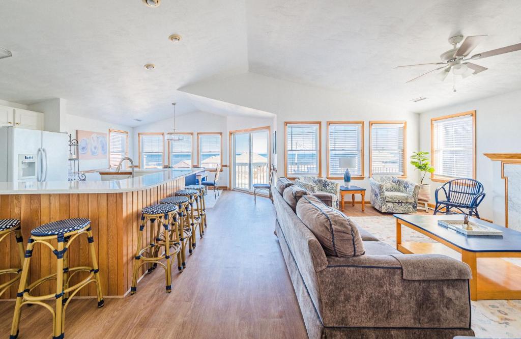 a living room with a couch and a bar with chairs at Sea Sun Greetings - Kitty Hawk MP 2.5, Ocean Views, Direct Beach Access, Pool, Hot Tub, Pets OK in Kitty Hawk