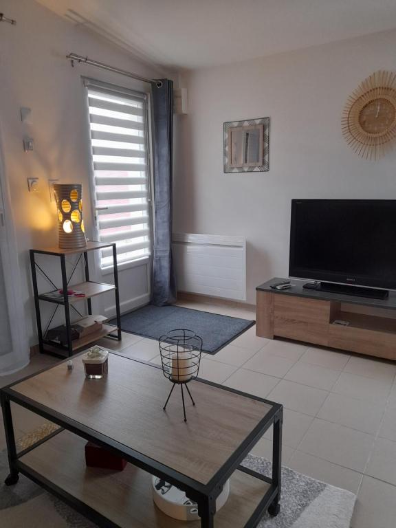 uma sala de estar com uma televisão e uma mesa de centro em La Pépite de l'océan em Saint-Nazaire