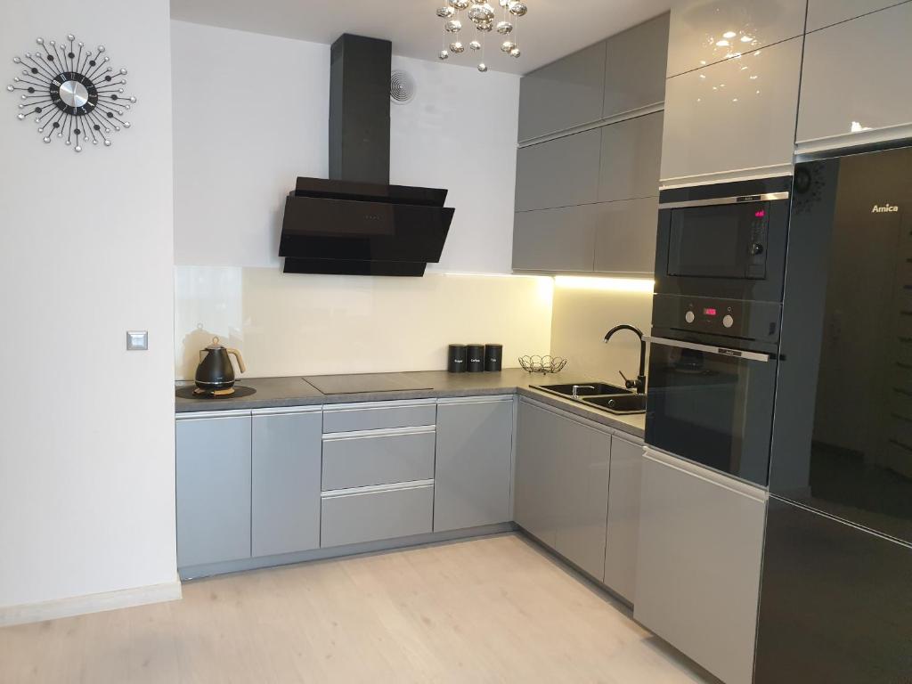 a kitchen with white cabinets and black appliances at Caskada Modern Apartment 3 in Słupsk