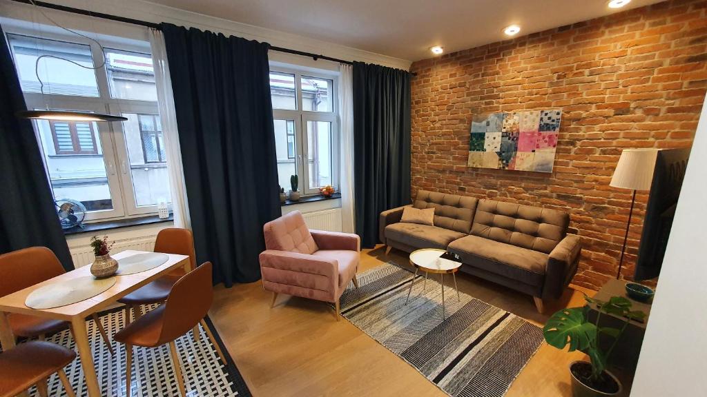 a living room with a couch and a brick wall at Apartamenty SIENKIEWICZA 8 in Żywiec