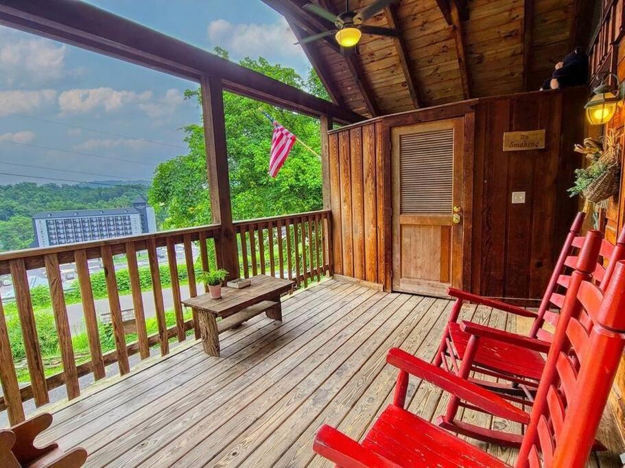 un porche con 2 sillas rojas y una mesa de picnic en Cozy Studio Log Cabin in the heart of Pigeon Forge. Hot Tub. Honeymoon! Sleeps 2 en Pigeon Forge