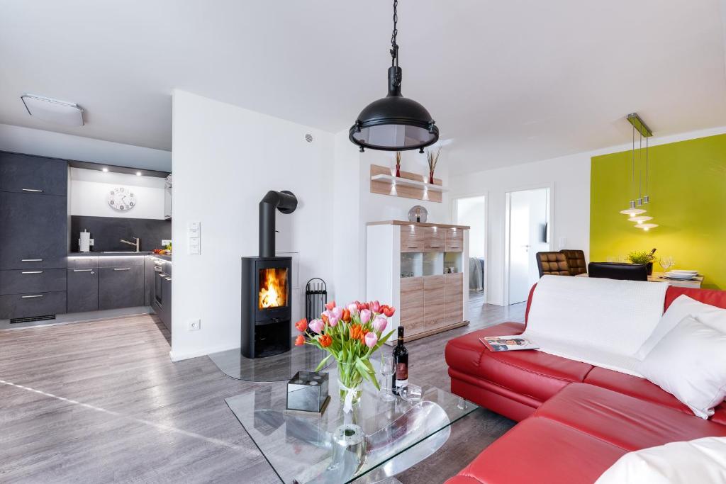 a living room with a red couch and a fireplace at Fewo Kapitän James Cook by Seeblick Ferien ORO, Wasserbett, E-Ladesäule, in Olpenitz