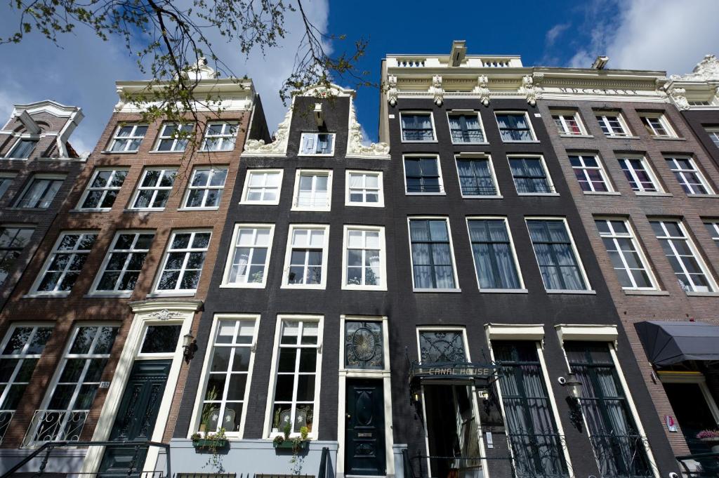 un edificio alto con ventanas blancas en una calle de la ciudad en Canal House en Ámsterdam
