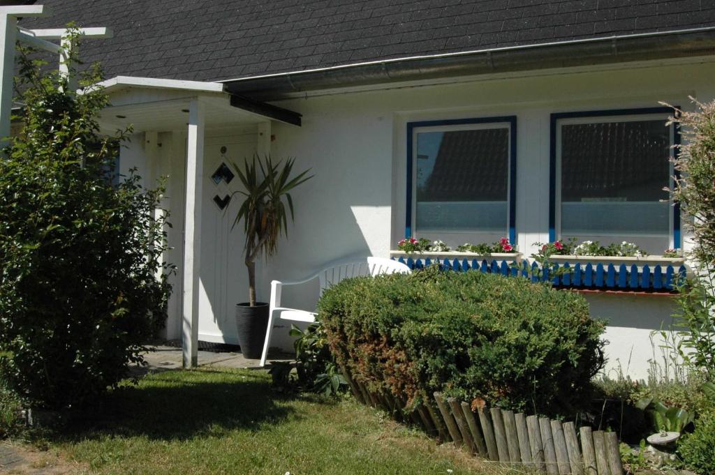 a white house with a bench in the front yard at Ruegen_Fewo 69 in Ummanz