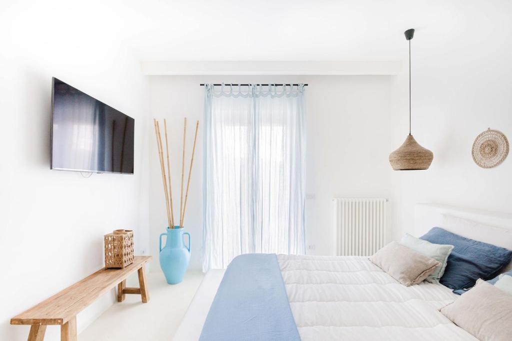 a white bedroom with a bed and a blue vase at Sole Suites in Sorrento