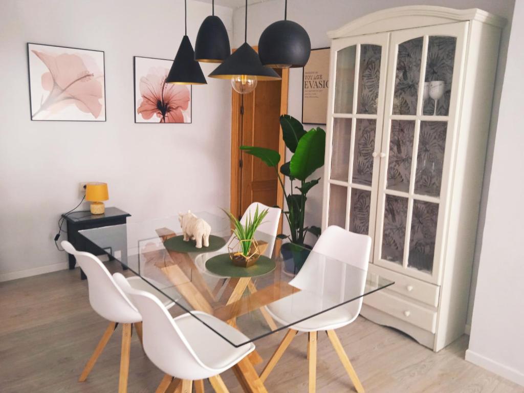 a dining room with a glass table and white chairs at Hipica Home Granada Center in Granada