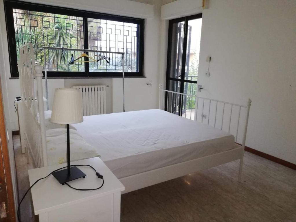 バーリにあるZona fiera Stanze in appartamento condivisoのベッドルーム1室(白いベッド1台、ランプ、窓付)