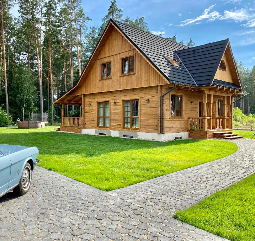uma casa de madeira com um carro estacionado em frente em Całoroczne domy z bala - CASA DEL CZYŻYK em Serwy