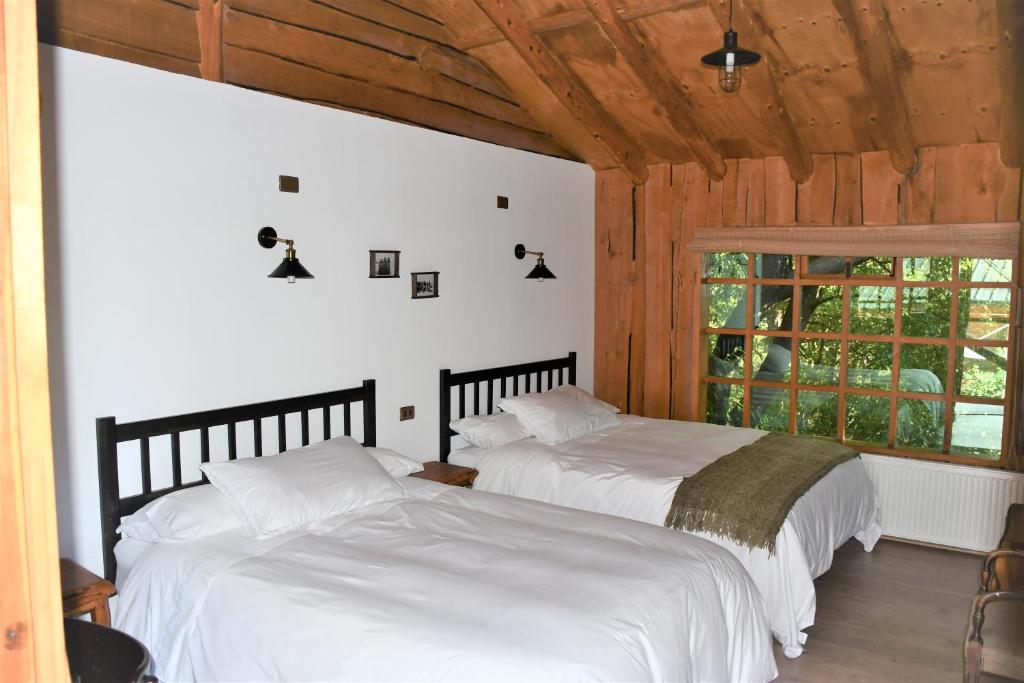 a bedroom with a large bed and a large window at Hotel El Barranco in Futaleufú