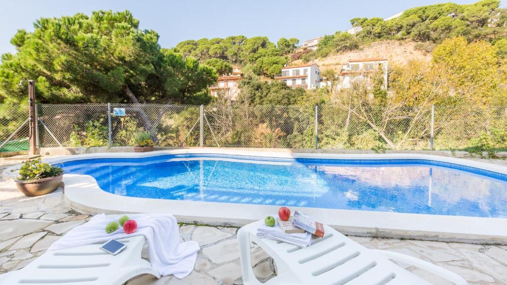 - une piscine avec 2 chaises longues blanches à côté dans l'établissement 2Pon01 - Lloret de Mar, à Lloret de Mar
