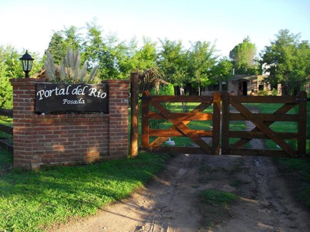 una puerta de madera con una señal frente a una valla en Portal del Río Posada en Santa Rosa de Calamuchita