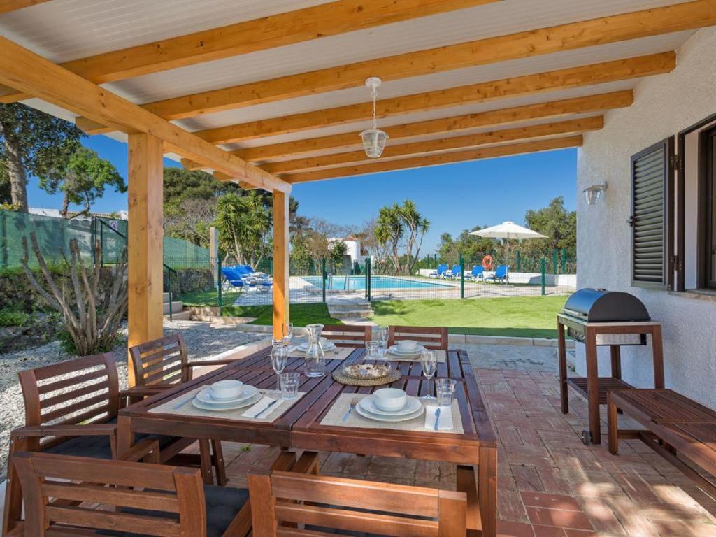 カルヴォエイロにあるCarvoeiro Peaceful Villa with Poolの木製テーブルと椅子付きのパティオ