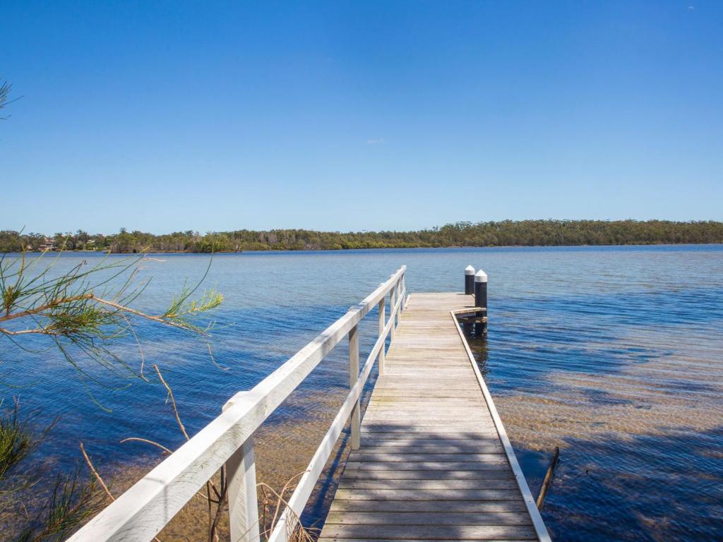 un puente de madera sobre un cuerpo de agua en Bayview I Absolute Waterfront with Jetty I 5 Mins to Hyams Beach, en Erowal Bay