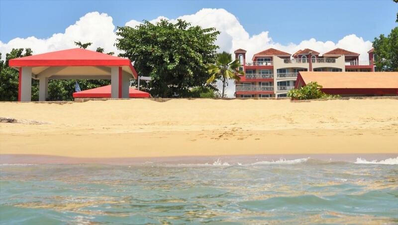 a beach with a red pavilion and a building at Seashore Condo in Rincon