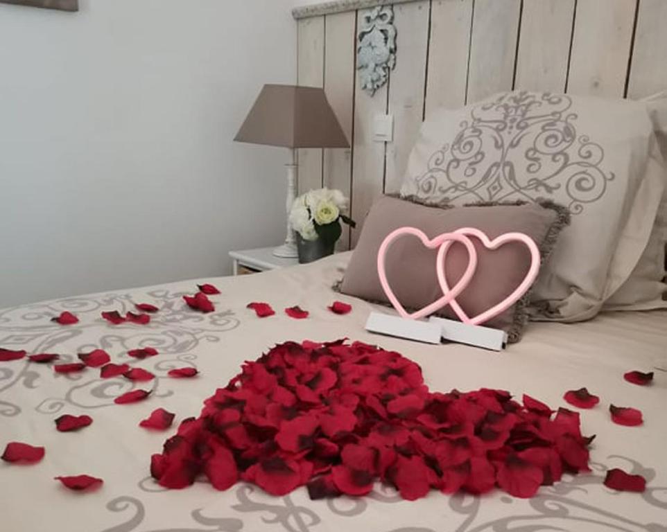 ein Haufen roter Rosen auf einem Bett mit einem rosa Herzen und einem Haufen in der Unterkunft SIANDAKI - logement romantique de charme in La Motte