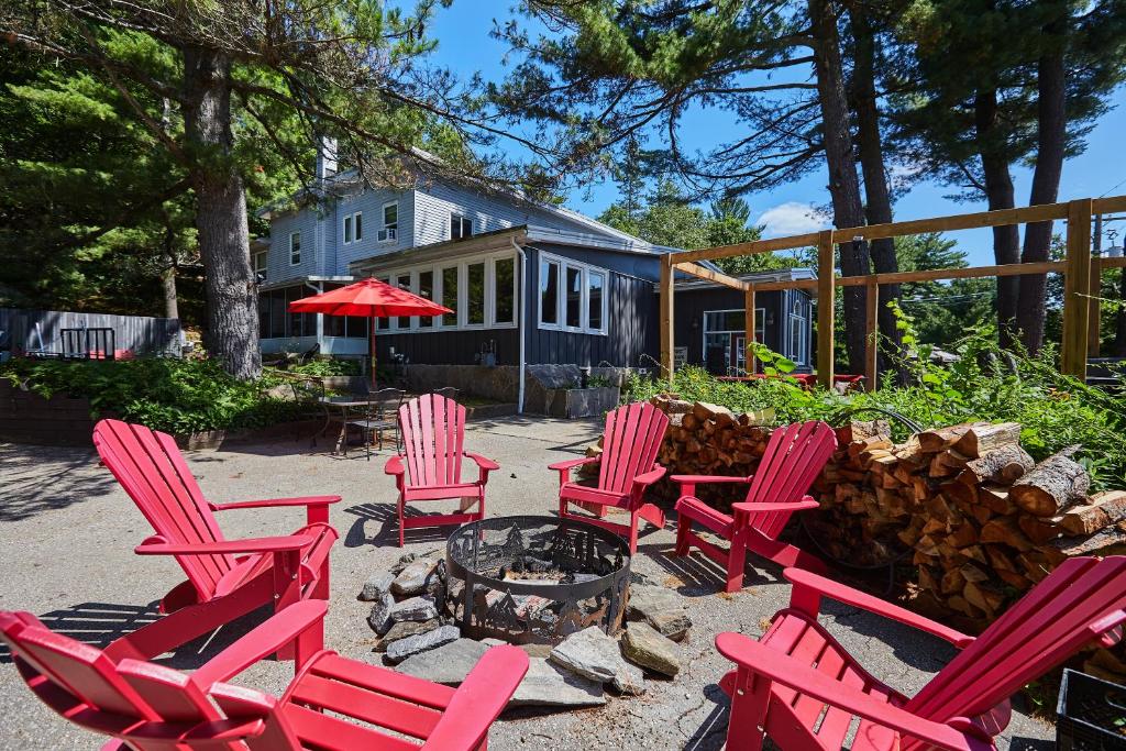 a group of red chairs sitting around a fire pit at 3 Pines Lodge Muskoka in Huntsville
