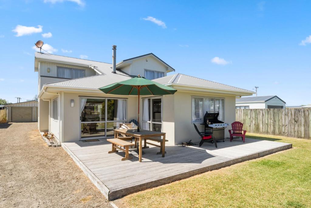 a house with a patio with a table and an umbrella at Hunia Haven - Himatangi Beach Holiday Home in Oroua Downs
