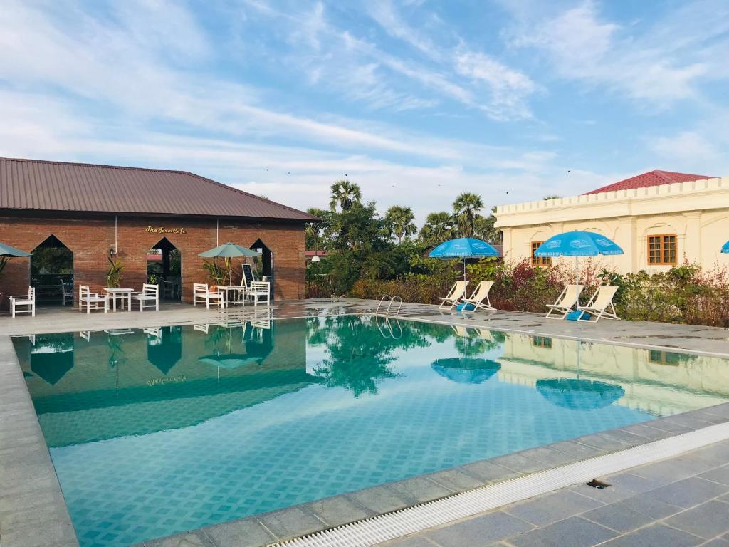 una gran piscina con sillas y sombrillas en E-Outfitting Royal Inn Bagan, en Myene