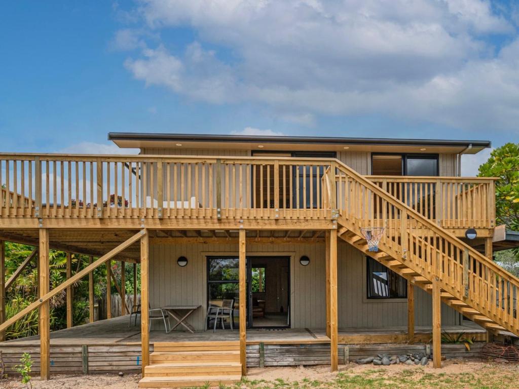 a house with a large deck and a staircase at All Decked Out - Matarangi Holiday Home in Matarangi