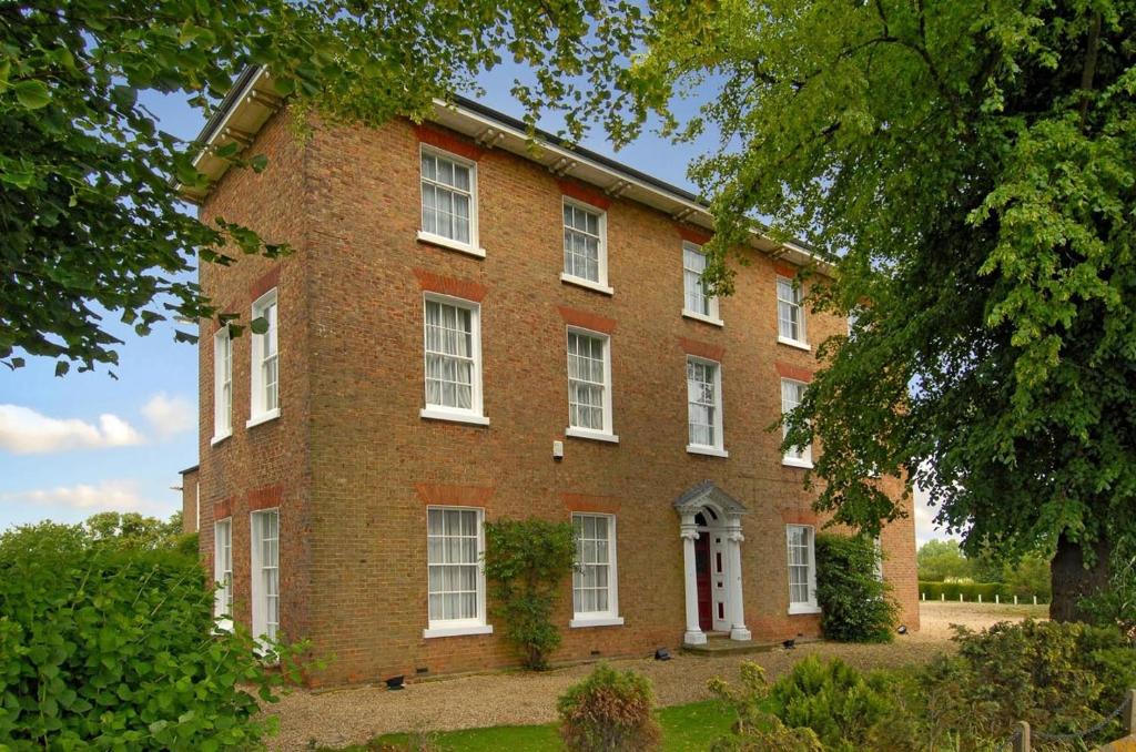 een groot bakstenen gebouw met witte ramen en bomen bij St Nicholas House in Spalding