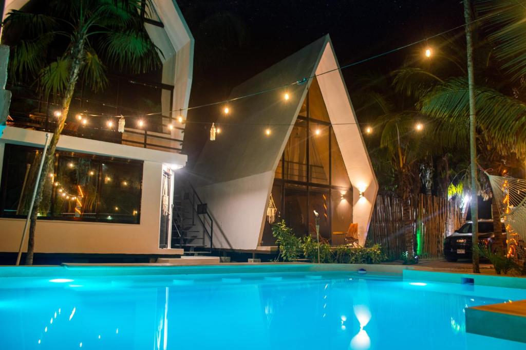 a swimming pool in front of a house at night at Xtambaa Cabins & Spa Only Adults in El Cuyo