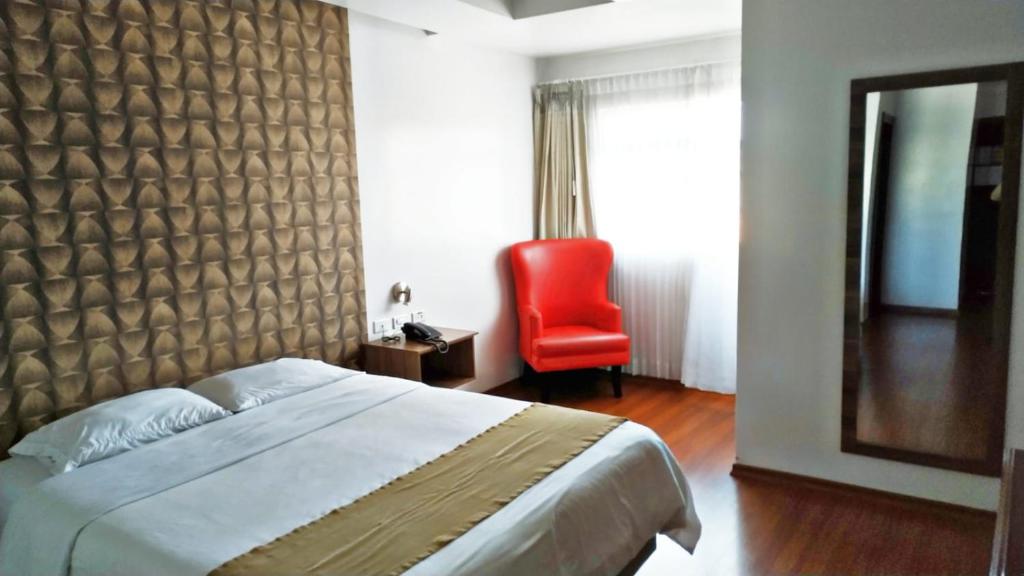 a bedroom with a bed and a red chair at HOTEL.TORRE ESPINOZA in Quito