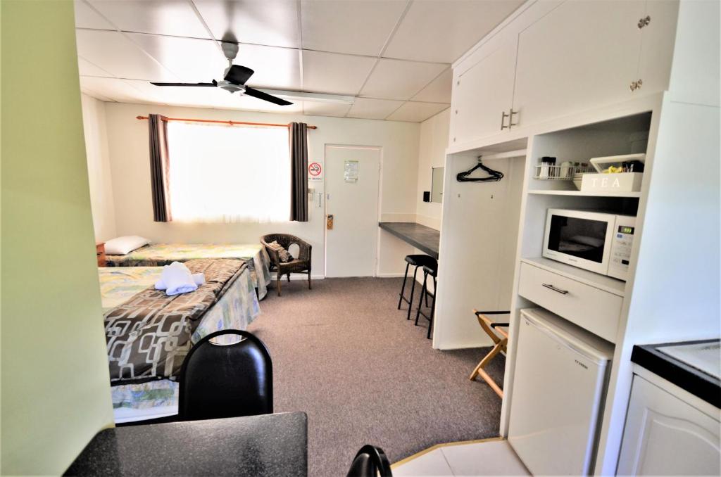a kitchen with a refrigerator, stove, microwave and a bed at Affordable Gold City Motel in Charters Towers