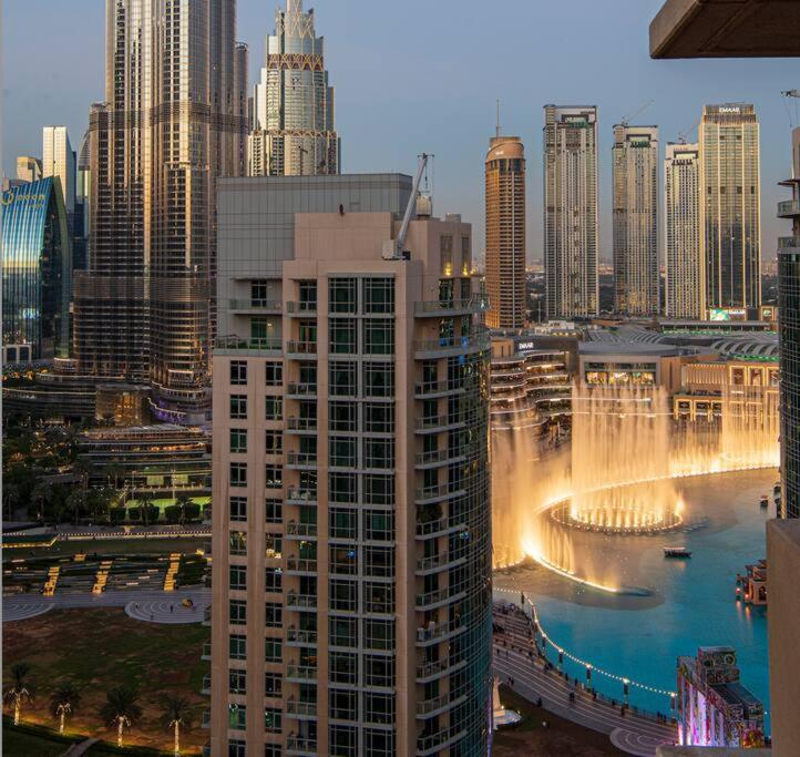 Hotel Luxury 2BR Burj Khalifa Fountain View with Pool, Gym, and Near Dubai Mall, a tall building with a fountain in the middle of a city at Luxury 2BR Burj Khalifa Fountain View with Pool, Gym, and Near Dubai Mall in Dubai