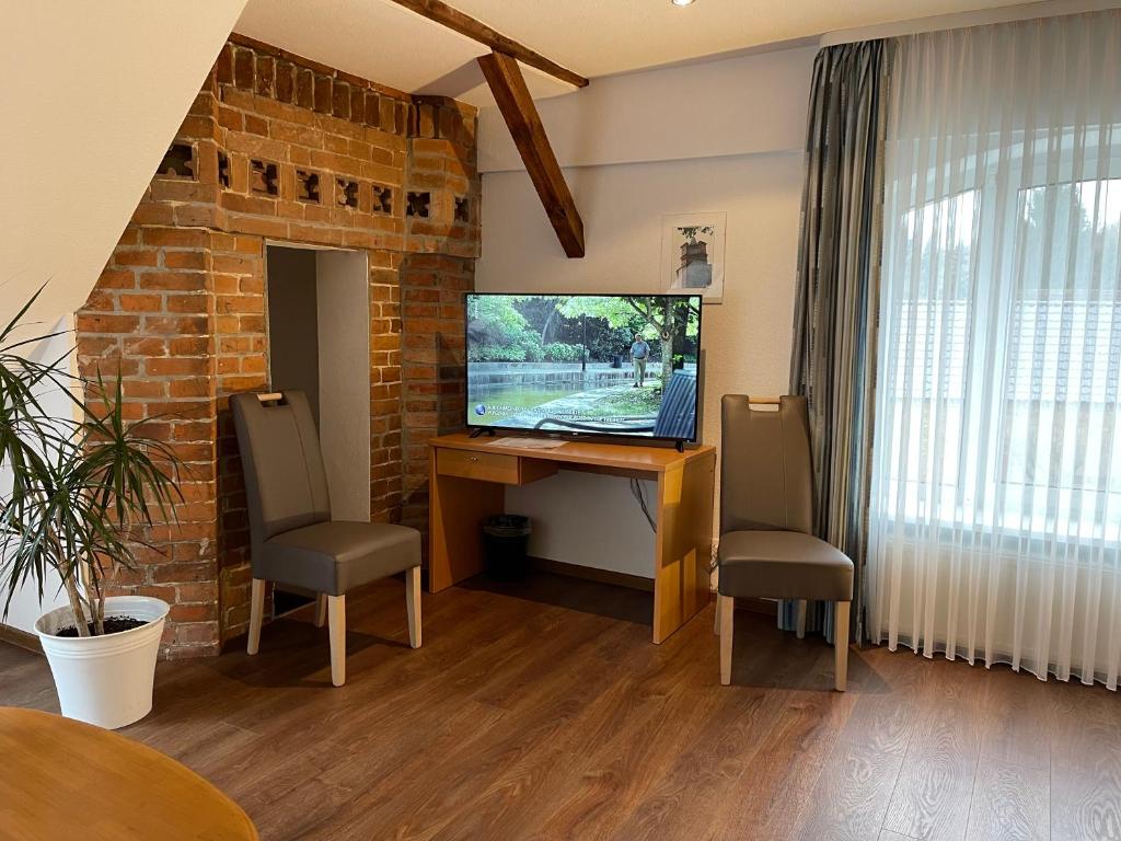 ein Wohnzimmer mit einem TV, einem Tisch und Stühlen in der Unterkunft Hotel Luther Birke Wittenberg in Lutherstadt Wittenberg