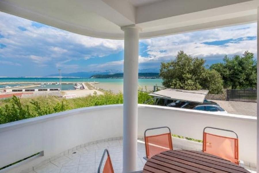eine Veranda mit einem Tisch und Stühlen sowie Meerblick in der Unterkunft Apartments Blue Skies - 30 m from the sea in Ljubač