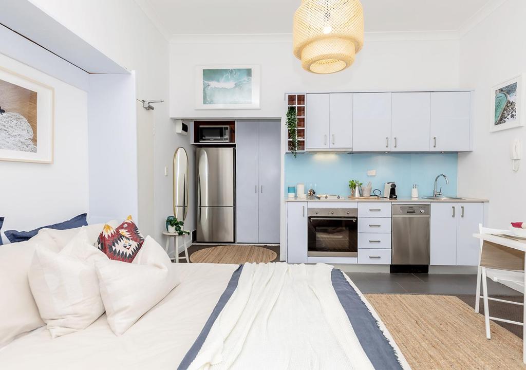 a white kitchen with a white bed in a room at COZY BEACH FRONT STUDIO WITH AIRCON in Sydney