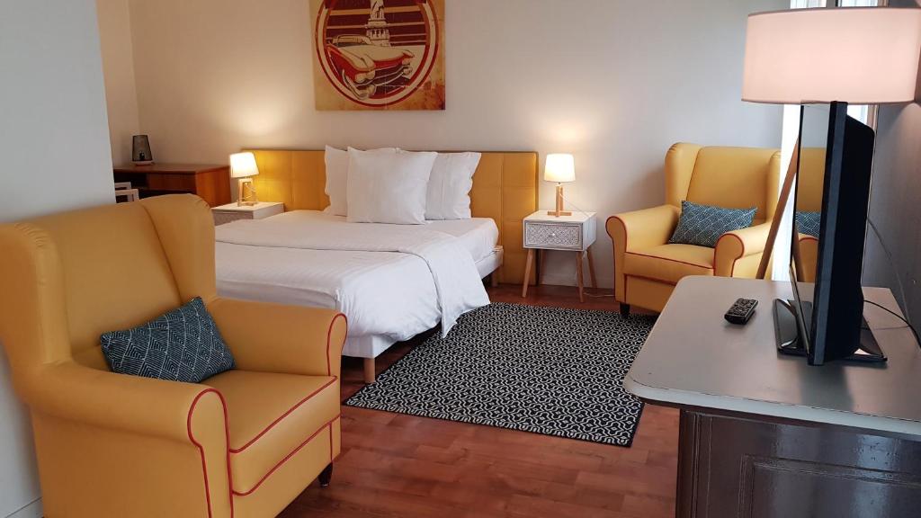 une chambre d'hôtel avec un lit et deux chaises dans l'établissement Résidence Carouge Appart Hôtel, à Brétigny-sur-Orge