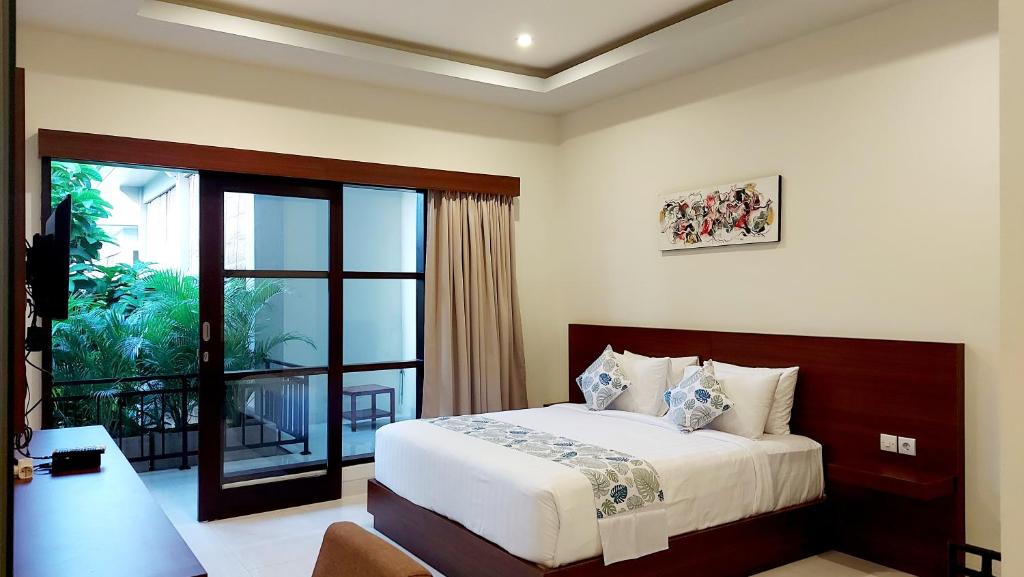 a bedroom with a bed and a balcony at The New Moon Seminyak in Seminyak