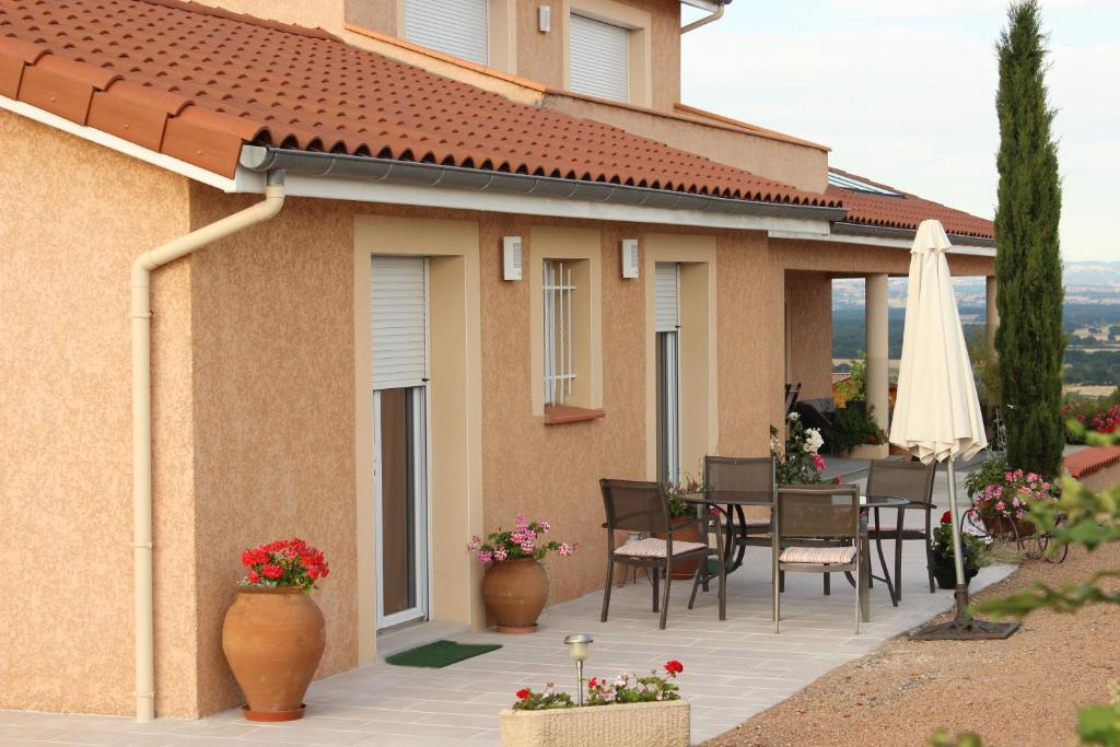 Cette maison dispose d'une terrasse avec une table et un parasol blanc. dans l'établissement Le Clos des Malézolles, à Saint-Germain-Laval