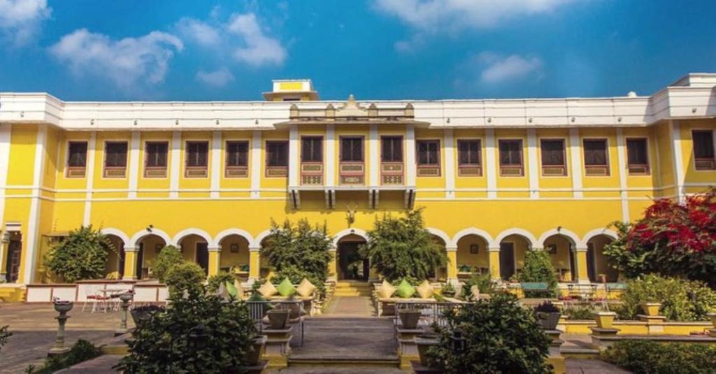 un edificio amarillo con un jardín delante de él en Bhanwar Vilas Palace, en Karauli