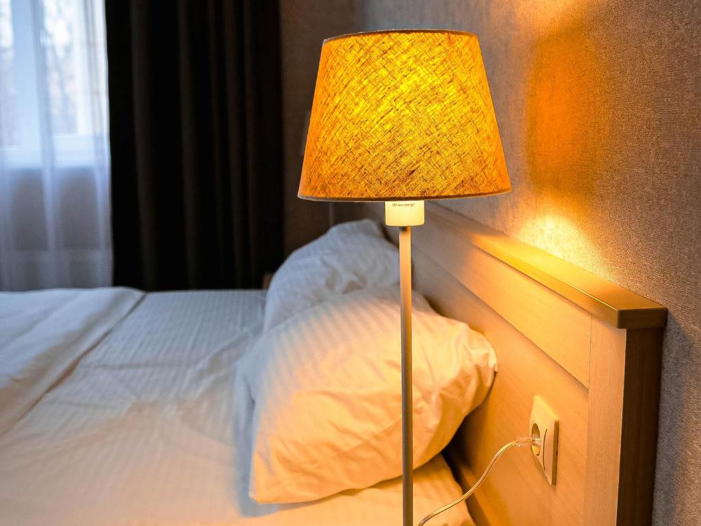 a lamp sitting next to a bed with a pillow at Магия КМВ in Kislovodsk