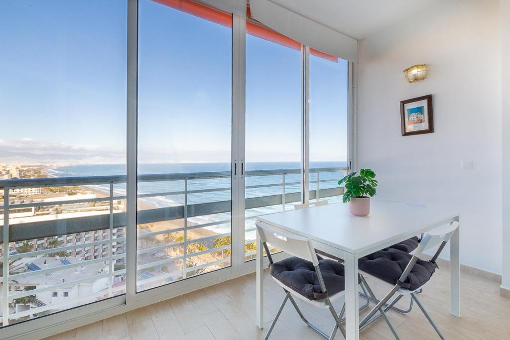 Una mesa y sillas blancas en una habitación con ventanas grandes. en ¡Magníficas vistas al mar! Piscina y wifi gratis, en Torremolinos