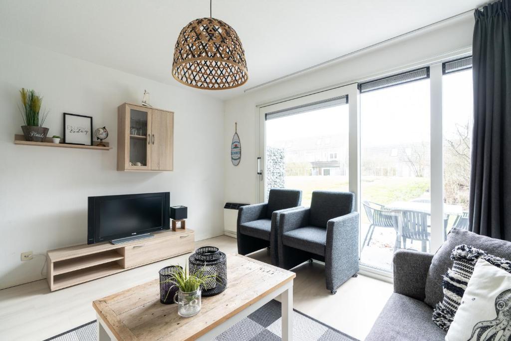 a living room with a tv and two chairs at Appartement NoorderKragt, Amelander Kaap in Hollum