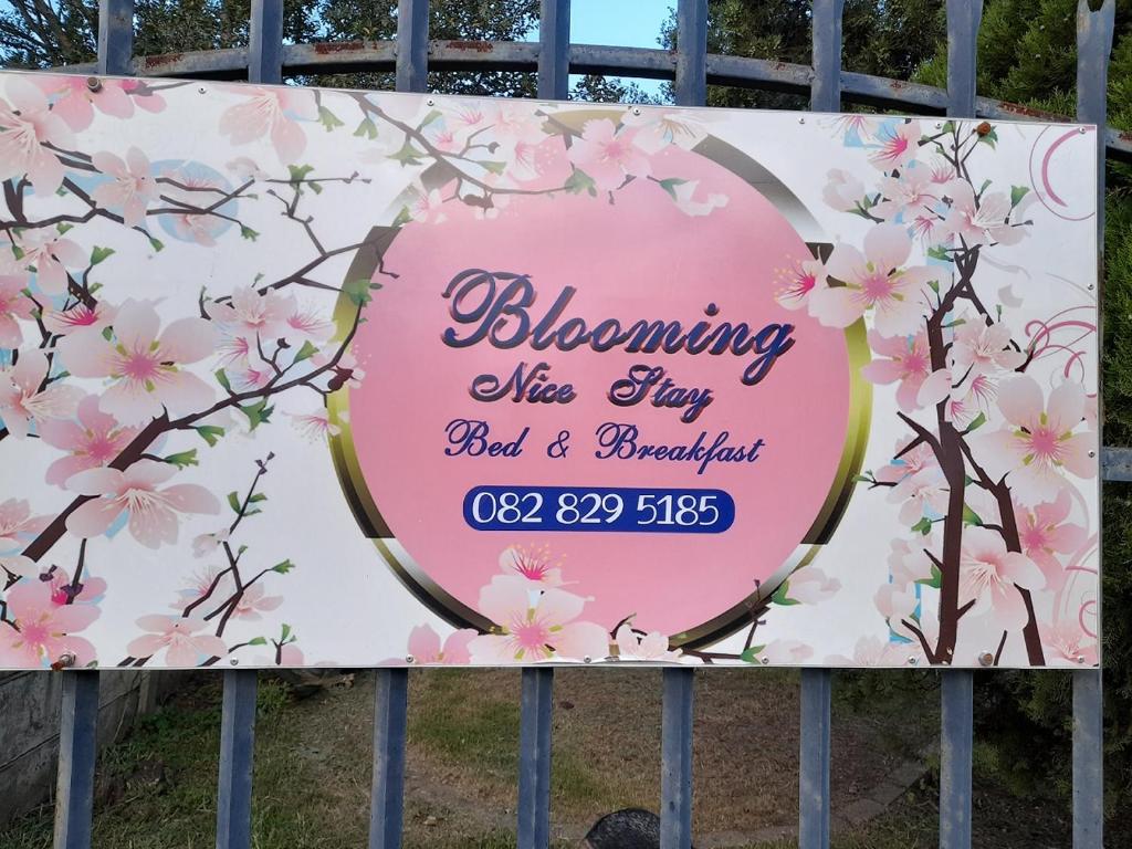 ein Schild auf einem Zaun mit einem rosa Kirschblütenschild in der Unterkunft Blooming Nice Stay in Harrismith
