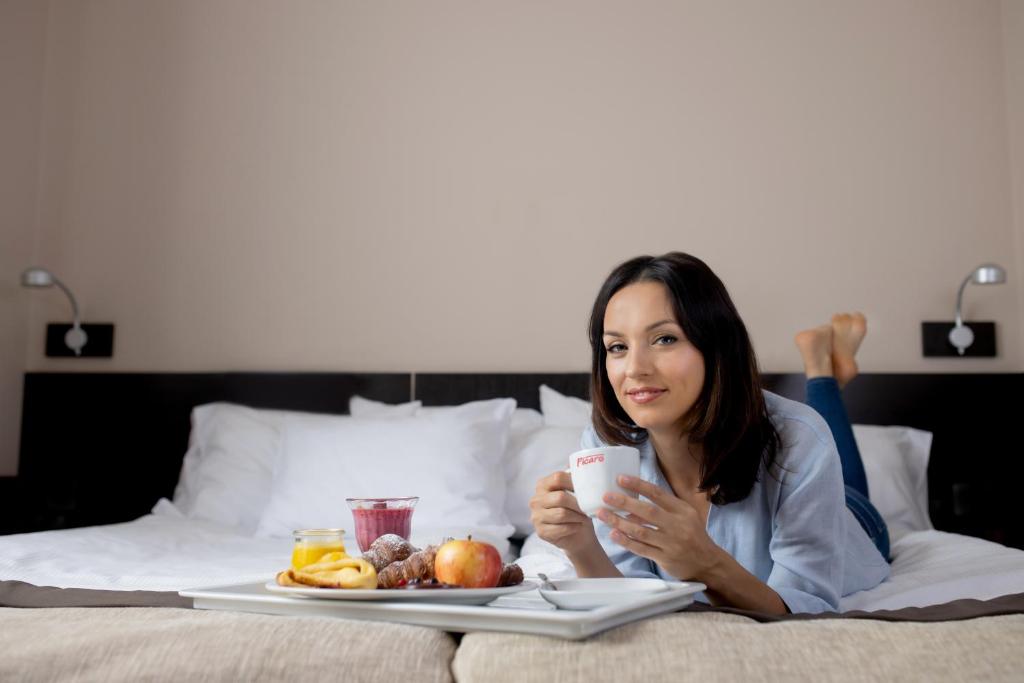 kobieta leżąca na łóżku z talerzem jedzenia w obiekcie Hotel Picaro Żarska Wieś Południe A4 kierunek Polska w mieście Zgorzelec